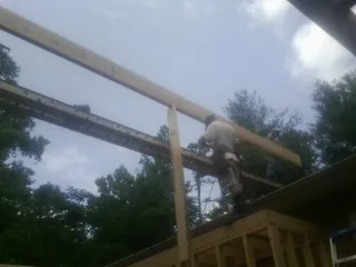 Carpenter setting a ridge beam over a new addition frame — Ice Dam Removal by Roofing Brothers in Kelly