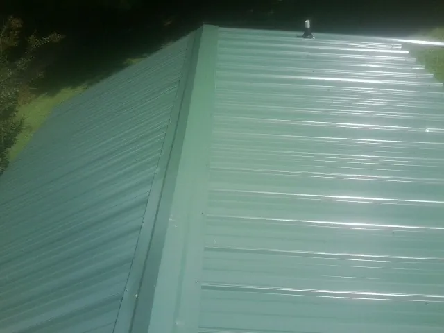 New green metal panels meeting at the ridge of a roof — Flat Roof Repair work by our crew in Kelly