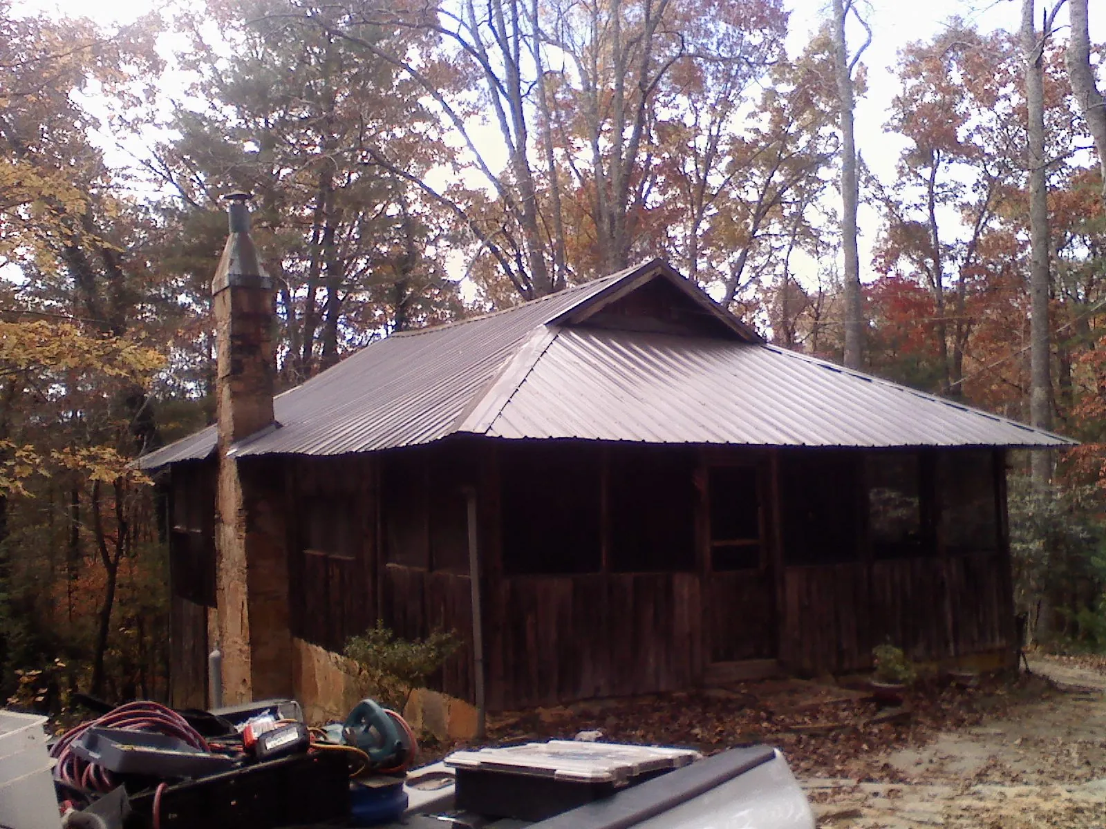 Brown metal hip roof on an old cabin with a stone chimney in Kelly