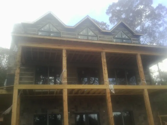 Dormers and porch framing on a large log home under construction — Roof Coating work by our crew in Kelly