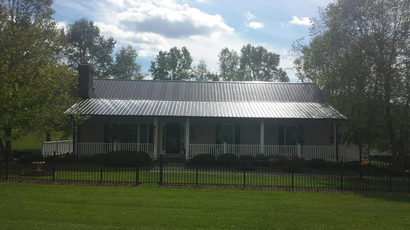 Gray metal roof on a brick ranch with a full width front porch — Gutter Guard Installation work by our crew in Kelly