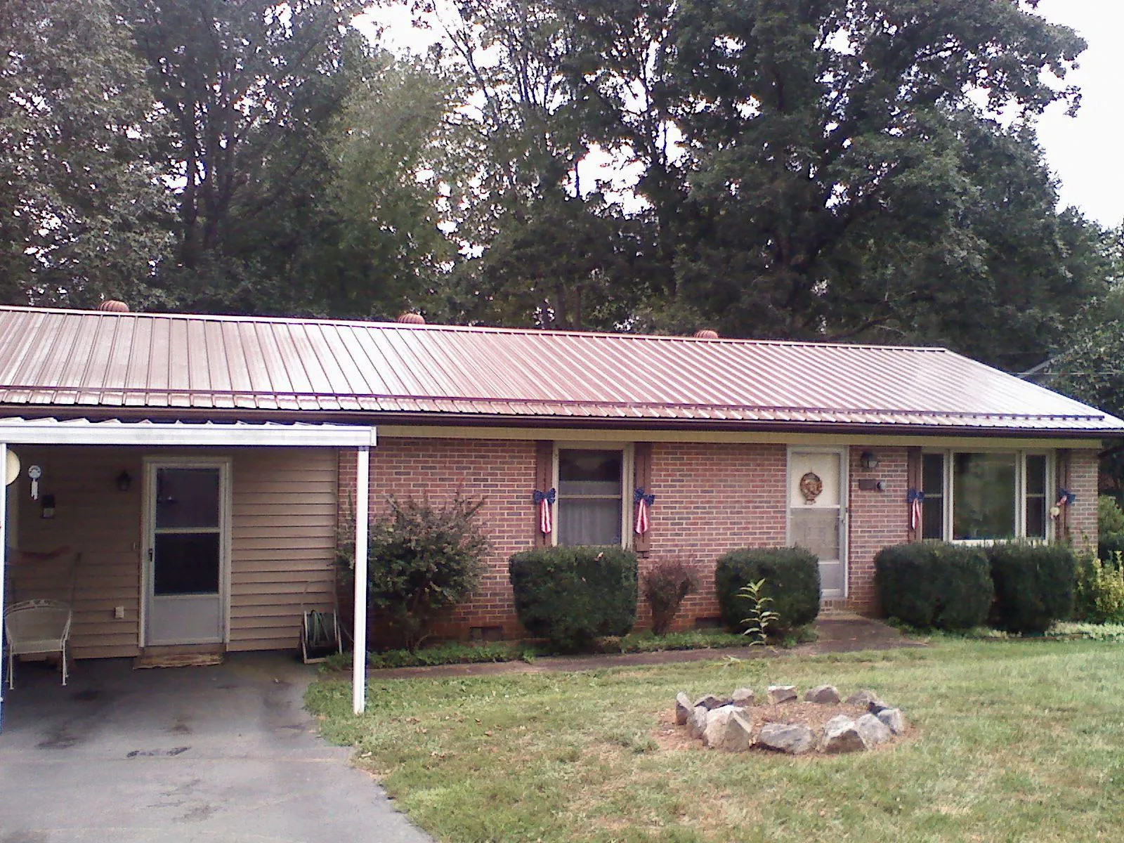 Bronze metal roof and carport on a brick ranch home — Roof Repair work by our crew in Kelly