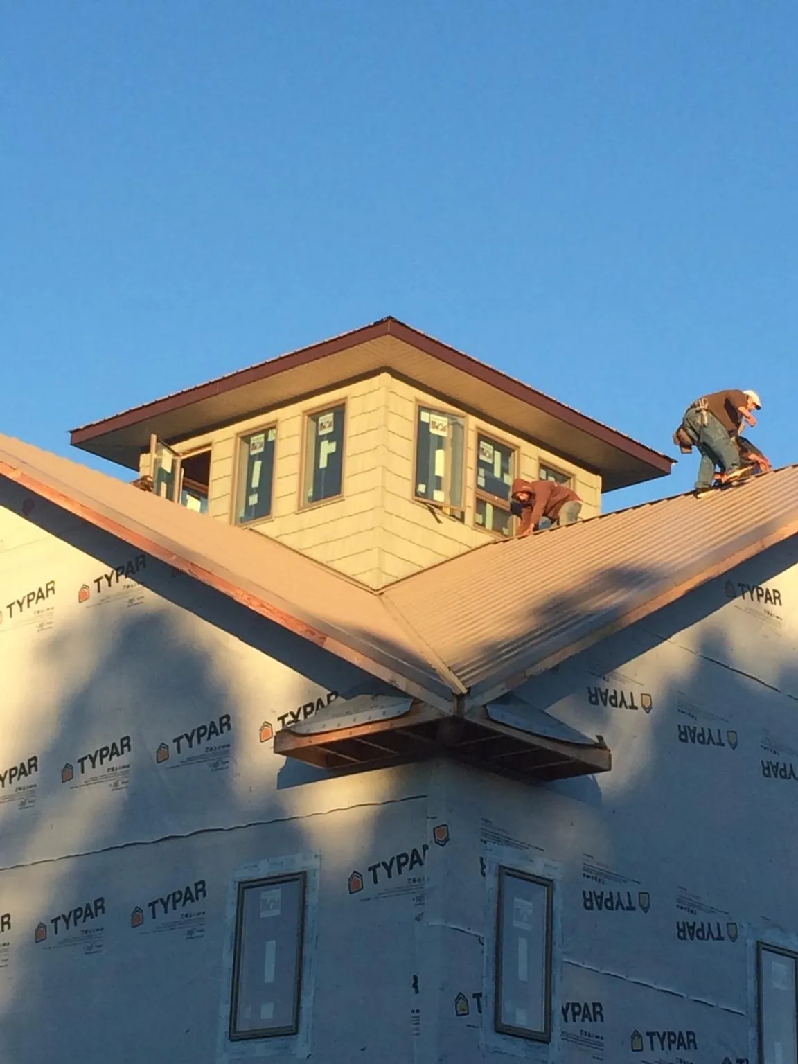 Roofers working around a rooftop cupola on a new metal roof at sunset — Roof Waterproofing in Kelly by Roofing Brothers
